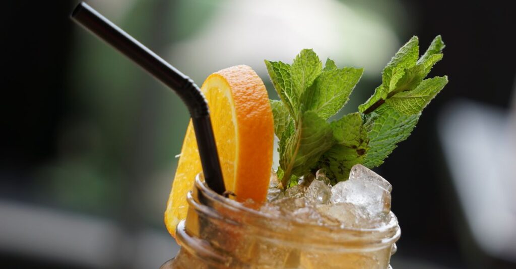 Close-up of a refreshing iced tea with orange slice and mint leaves, perfect for a hot day.