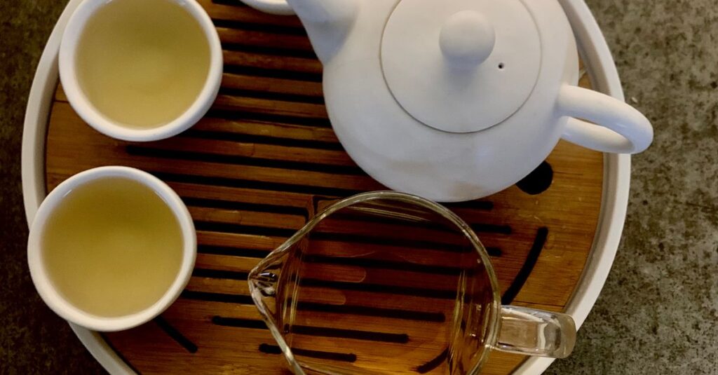 Overhead view of a tea set including a teapot and cups on a bamboo tray, perfect for serene tea time settings.