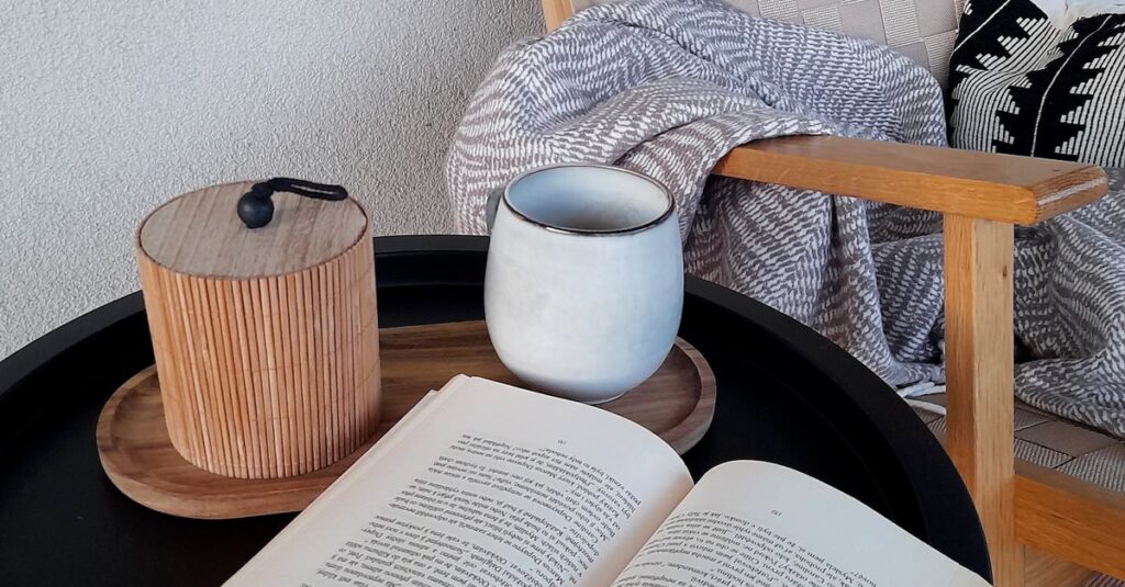 Relaxing corner with a book, mug, and a cozy blanket in a chair.
