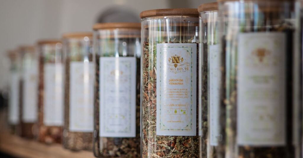 A selection of glass jars filled with herbal teas displayed on an indoor shelf.