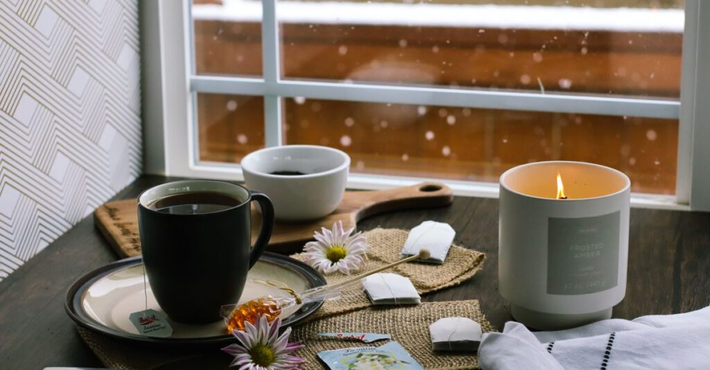 Warm indoor setting with tea, candles, and flowers on a snowy day.