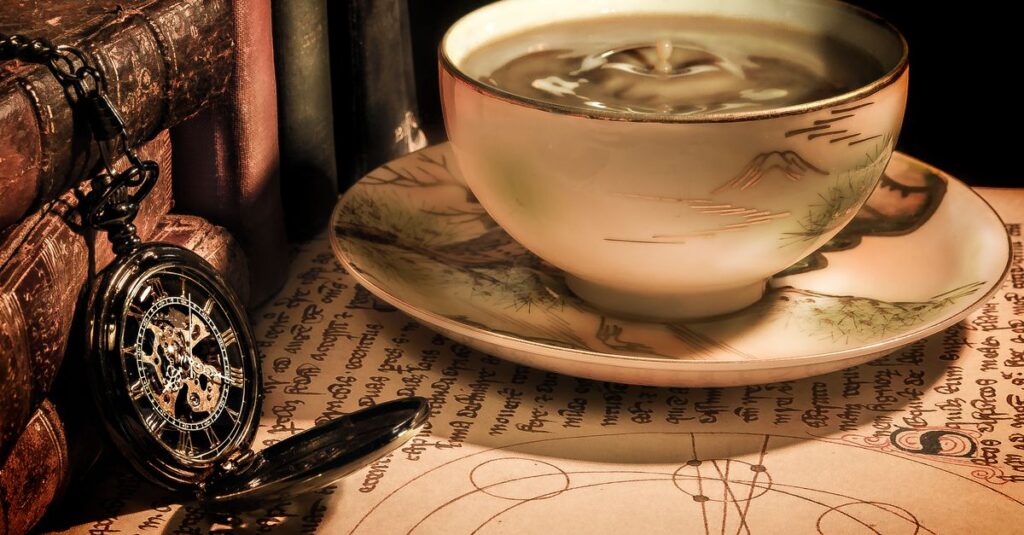 Elegant composition of a cup of coffee with a vintage pocket watch and books on a table.