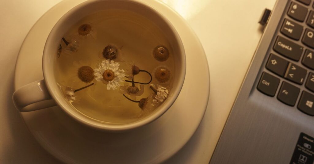 A soothing cup of chamomile tea next to a laptop, perfect for relaxation or work breaks.