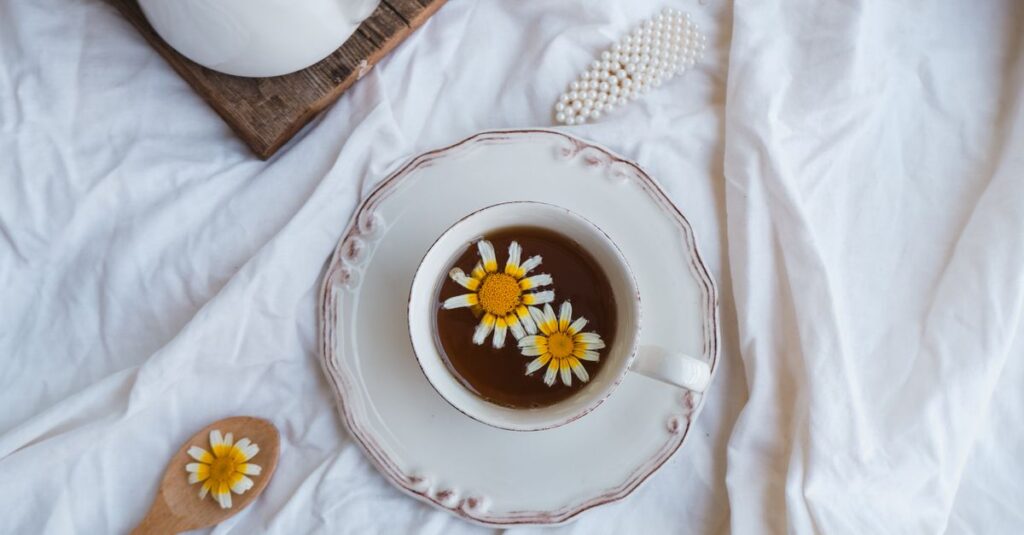 Enjoy a tranquil moment with chamomile tea, daisies, and rustic charm in a cozy setting.
