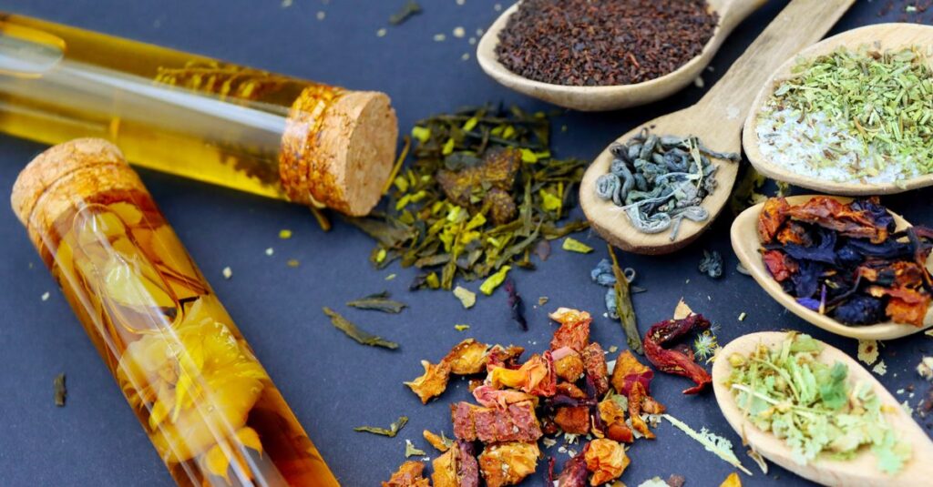 Colorful assortment of loose leaf teas and spices displayed on wooden spoons with test tubes.