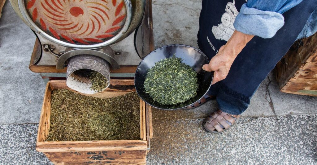 A person preparing green tea leaves using traditional methods in Kurashiki, Japan.