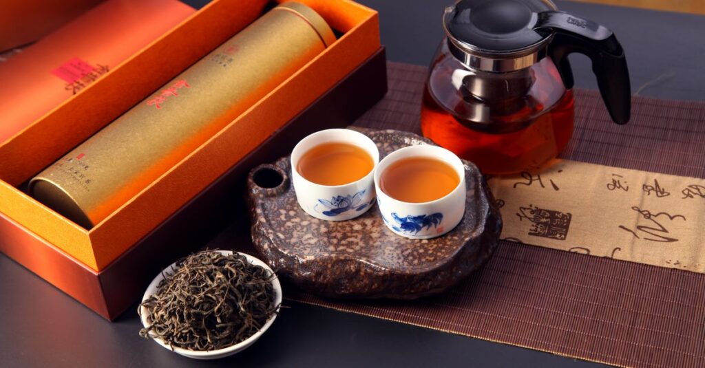 A beautifully arranged Chinese tea ceremony featuring teapot, cups, loose leaves, and an elegant gift box.