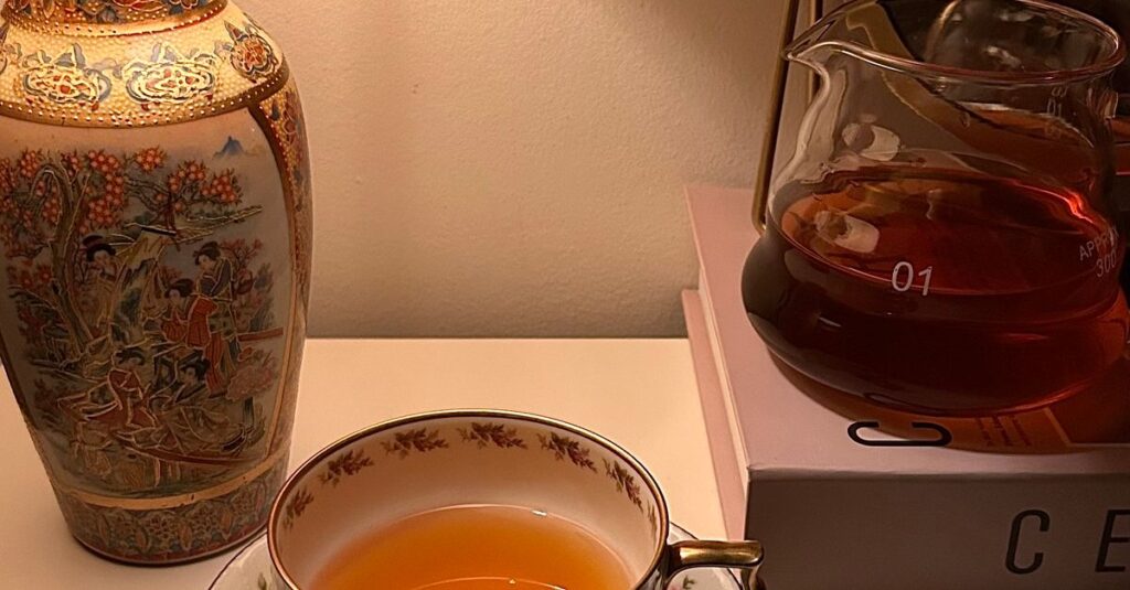 Warm and inviting scene with a vintage lamp and tea setup on a table, perfect for relaxation.