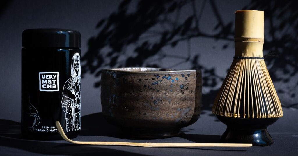 A traditional matcha tea ceremony setup featuring bamboo whisk, matcha bowl, and tea caddy.