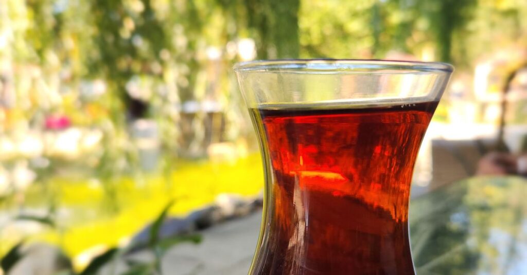 Capture the essence of İstanbul with Turkish tea in a tulip glass set against a vibrant outdoor backdrop.