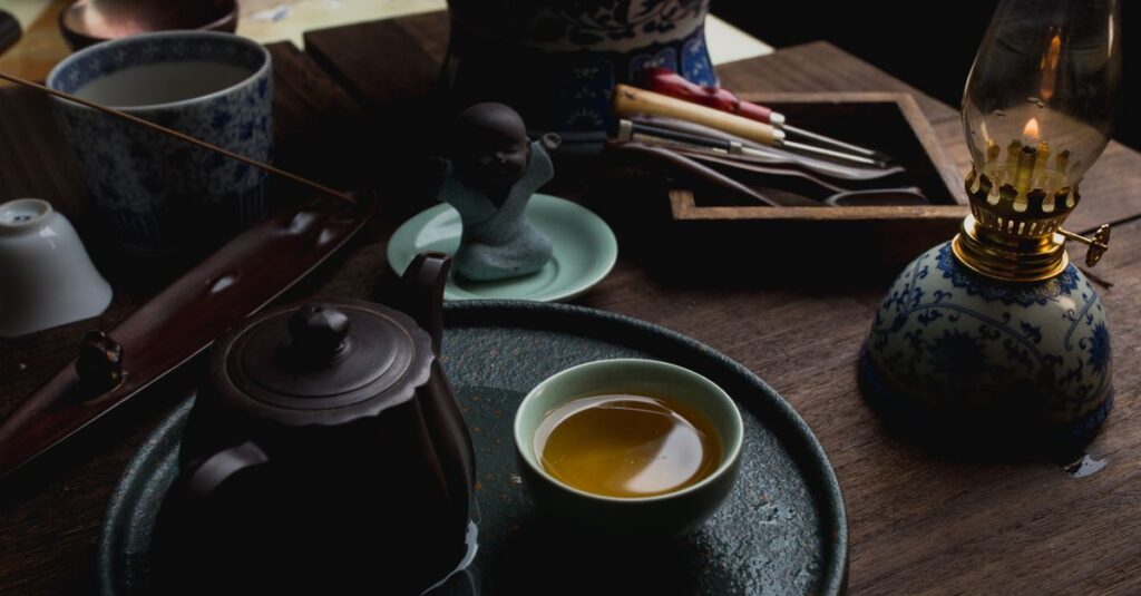A cozy setup featuring a teapot, tea cup, and lantern on a wooden table, evoking warmth and tradition.