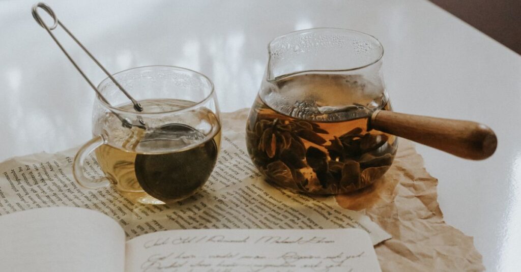 A warm tea scene with a glass cup, teapot, and open journal, evoking cozy indoor vibes.
