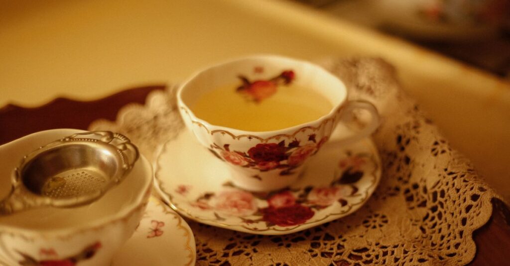 Elegant floral teacup with tea served on lace placemat, offering a vintage aesthetic.
