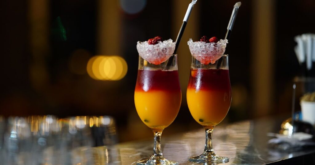 Two vibrant cocktails with berries and ice, set in a stylish bar setting.