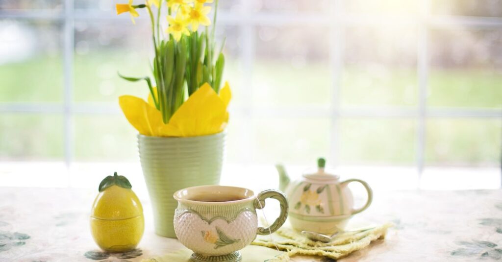 A charming spring tea setup featuring daffodils, a teapot, and cup in bright sunlight.