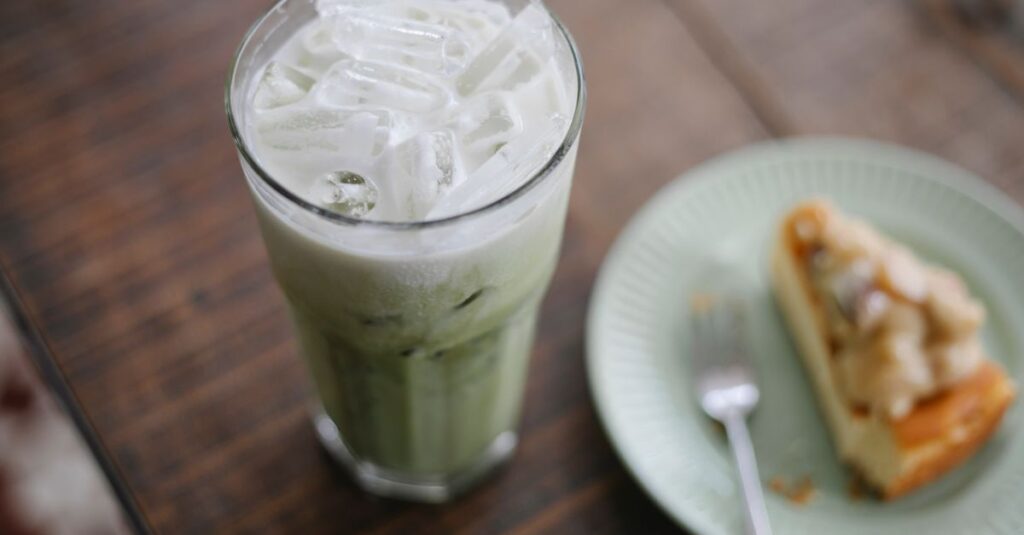 From above iced matcha tea latte served with yummy cake slice on table