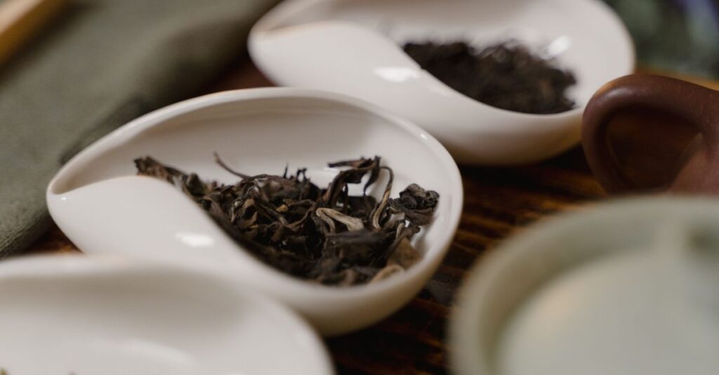 Porcelain dishes holding various loose tea leaves, highlighting traditional tea culture.