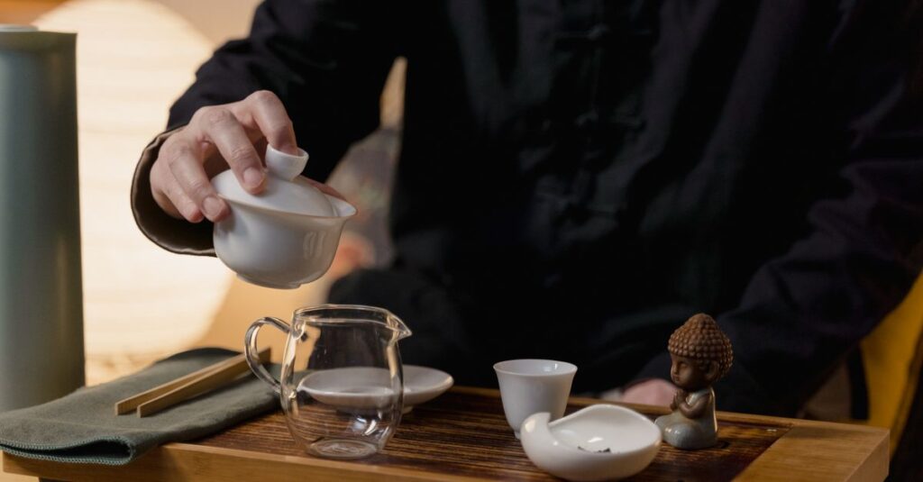 Explore a serene tea ceremony showcasing a traditional ceramic tea set on a wooden board indoors.