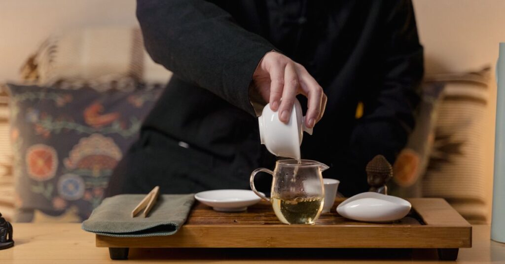 A person performing a traditional Chinese tea ceremony with a gaiwan and cha hai set.