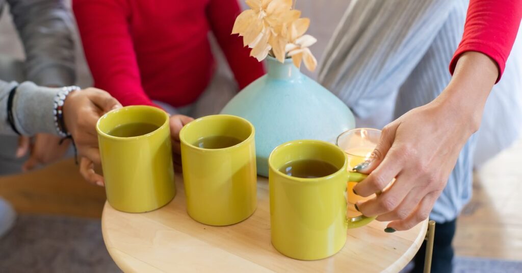 Warm setting with mugs of tea and a vase on a wooden table, promoting comfort and togetherness.