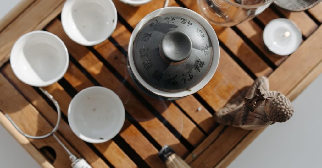 Traditional tea ceremony set on a wooden tray with teapot and cups captured from above.