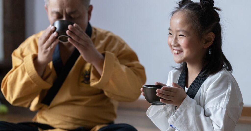 Elderly man and young girl enjoying tea together in traditional attire.