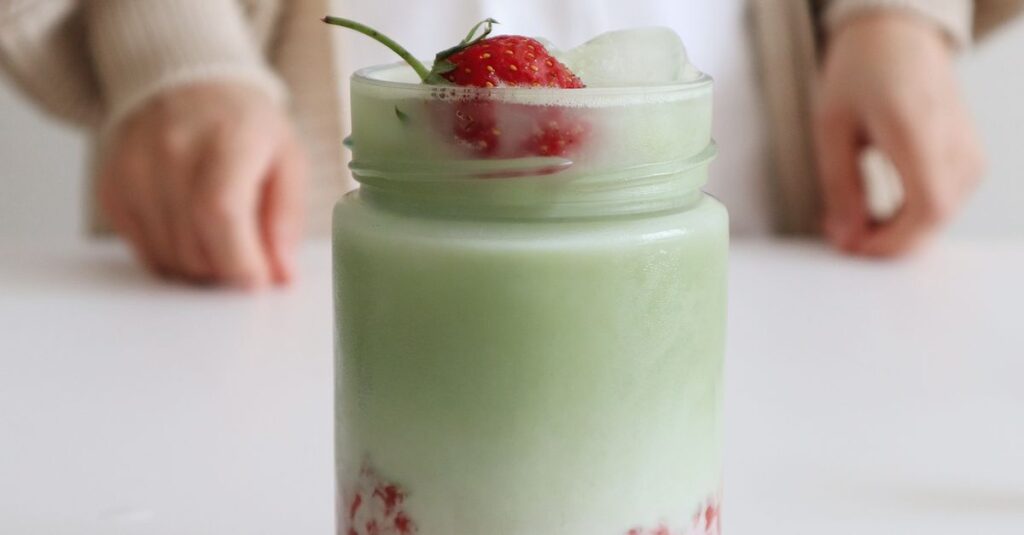 Delicious homemade strawberry matcha latte with ice served in a glass jar. Perfect for a refreshing break.