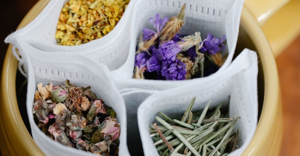 Top view of various herbal teabags with flowers in a yellow mug on a wooden table.