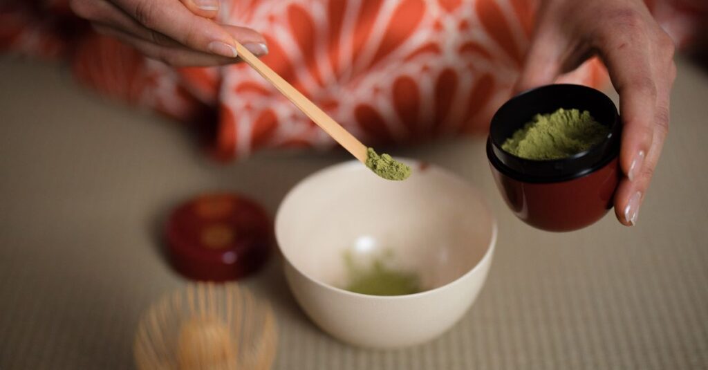 Close-up of a woman preparing matcha tea in a traditional Japanese tea ceremony setting.