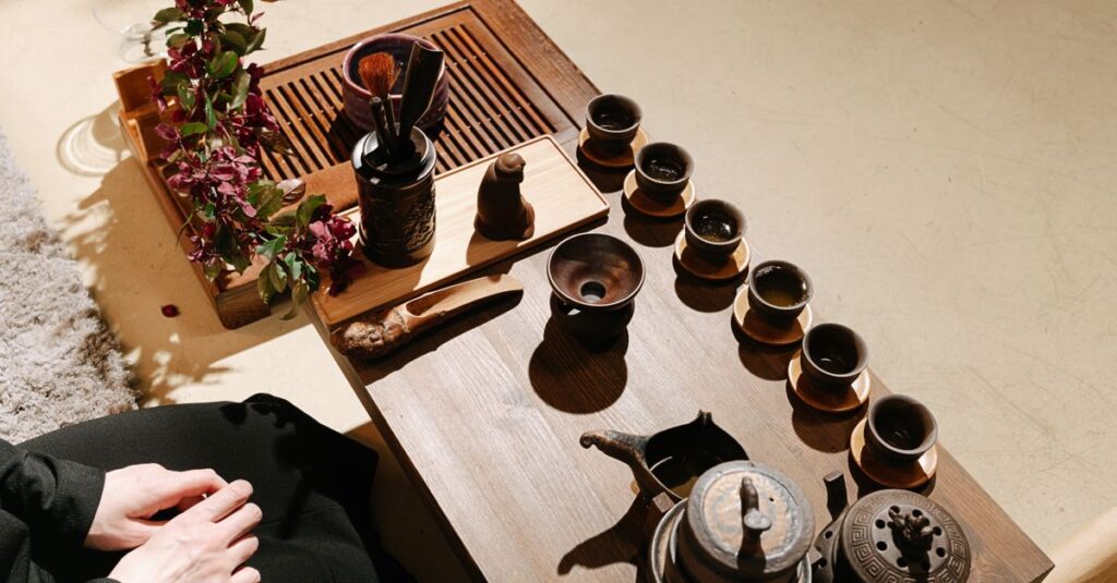 Elegant tea ceremony setup with cups and accessories on a wooden table.